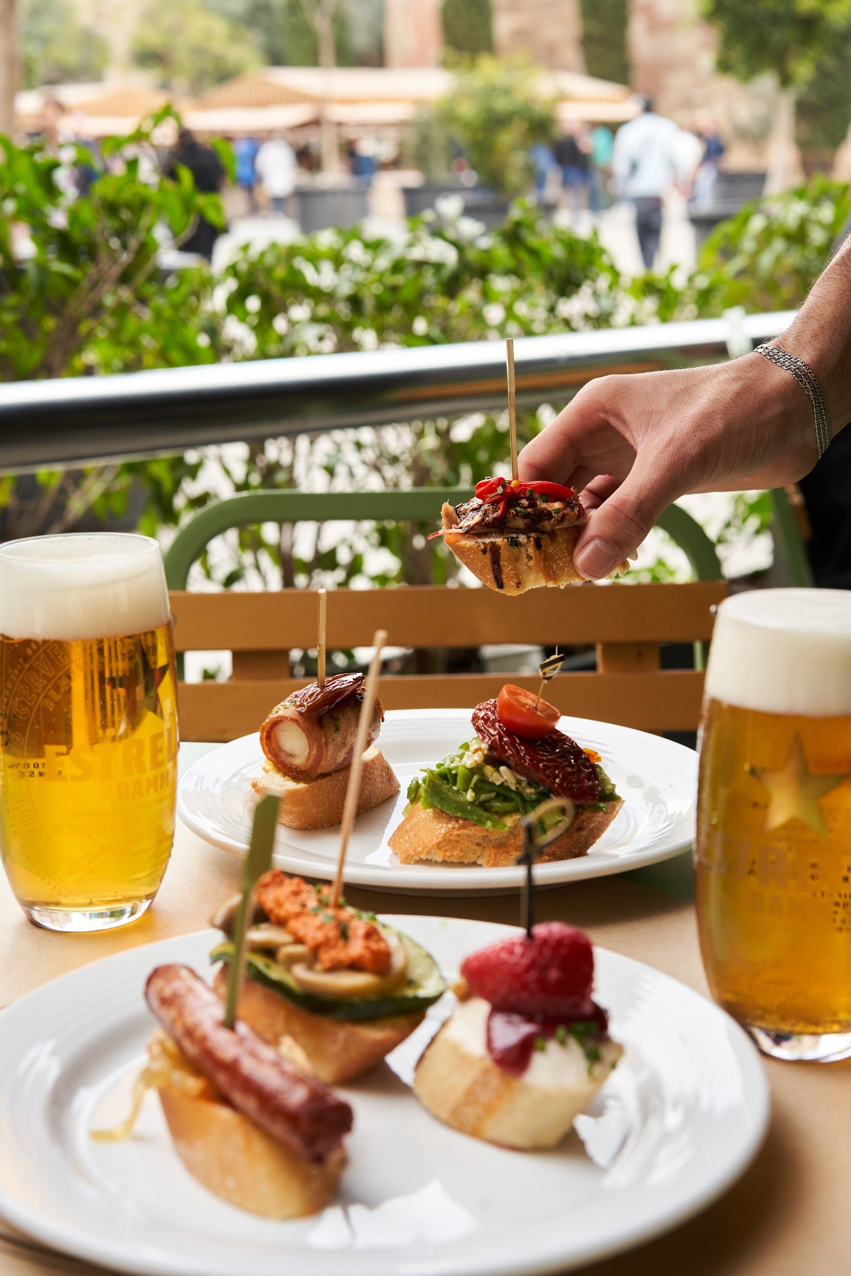 Imagen de mesa de terraza con platos con pinchos y cerveza